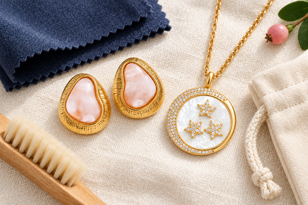 Boss Up Organic Glow earrings and Rise and Shine necklace arranged with a polishing cloth and jewelry-care brush