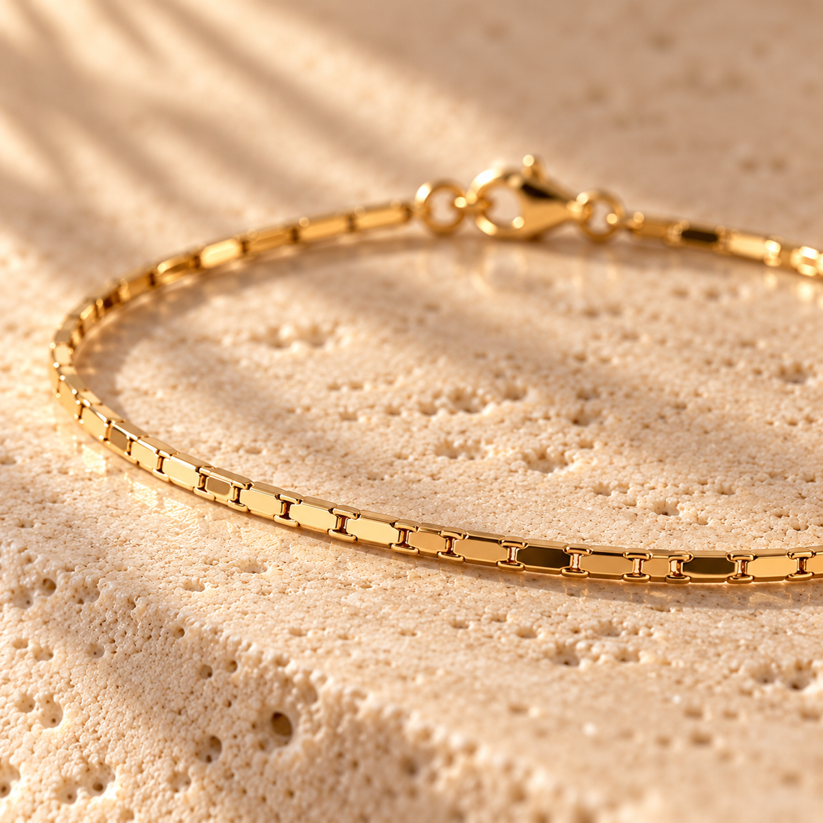 Thin Margin bracelet macro close-up: flat polished gold links and lobster clasp