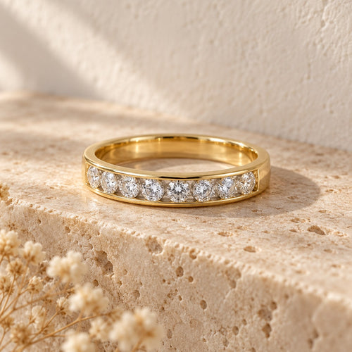 Straight Talk channel-set band in gold on a travertine ledge