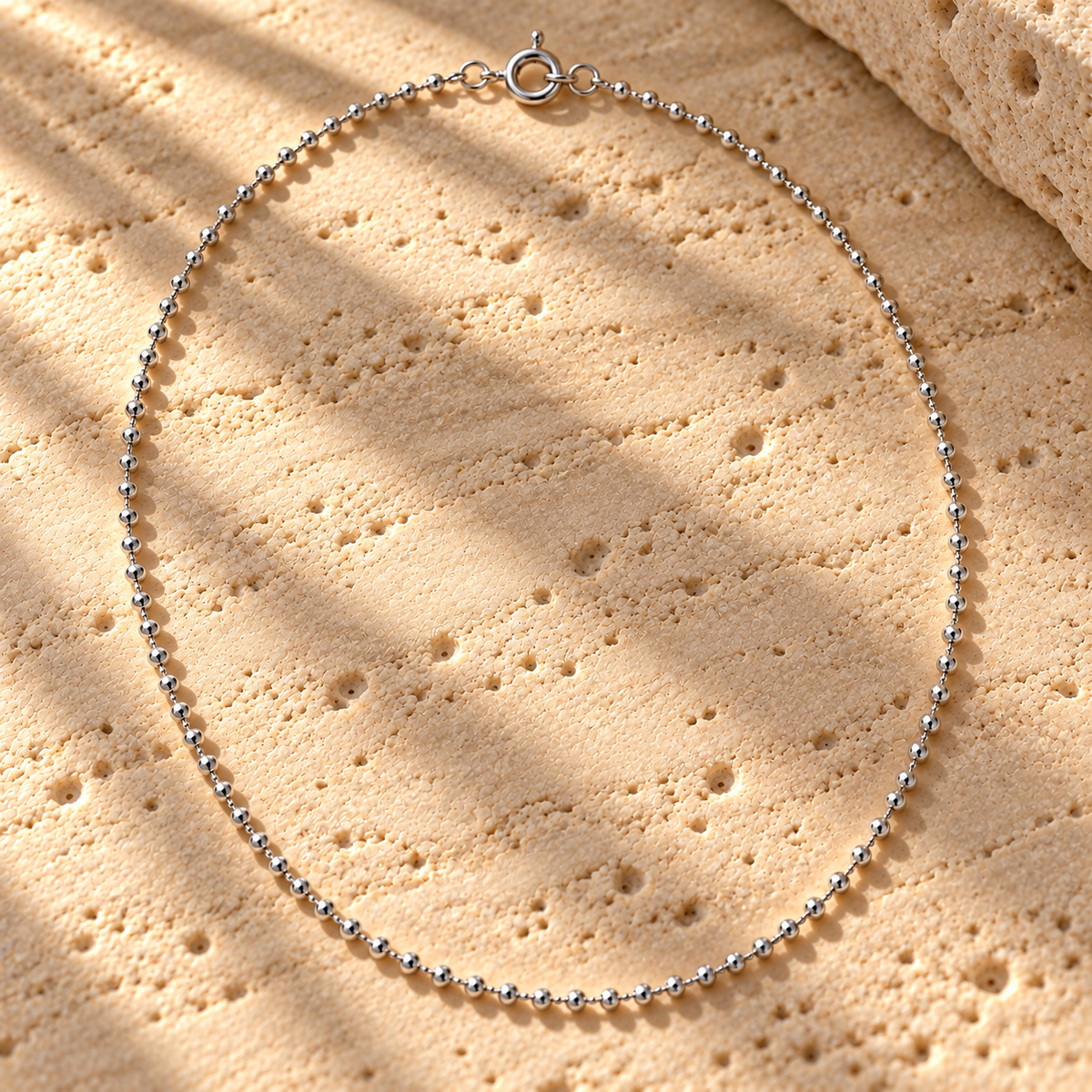 Bar None bead chain in sterling silver laid on travertine, polished beads and spring-ring clasp